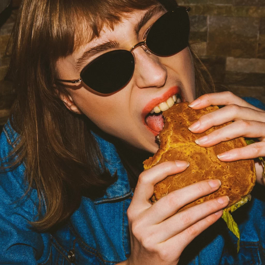 Morel - Azur - vrouw - jeans - zonnebril - eten - hamburger
