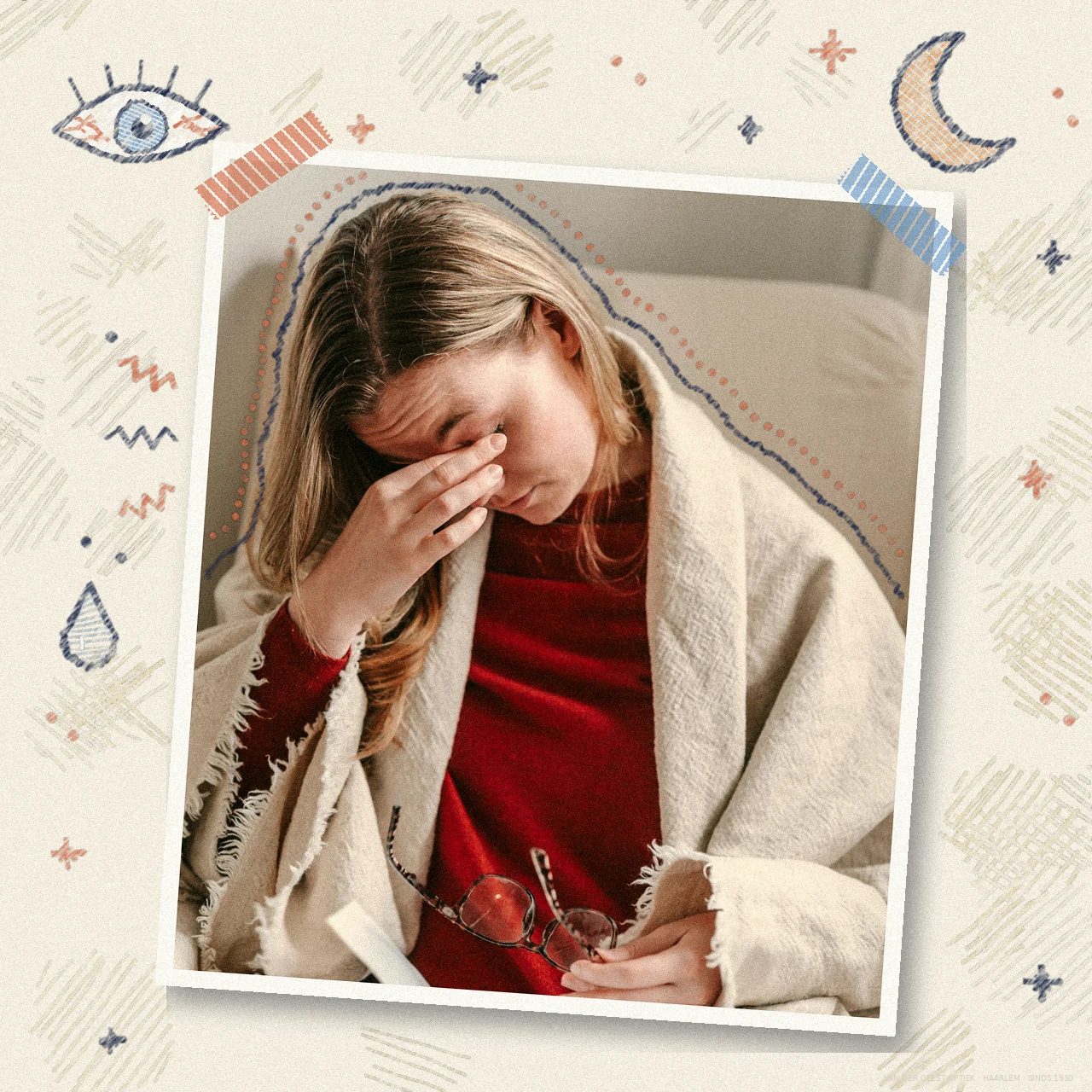 Vrouw in een deken wrijft in haar oog met haar bril in de hand, met krijttekeningen van een oog met rode adertjes, een maantje en een druppel, als beeld bij rode ogen